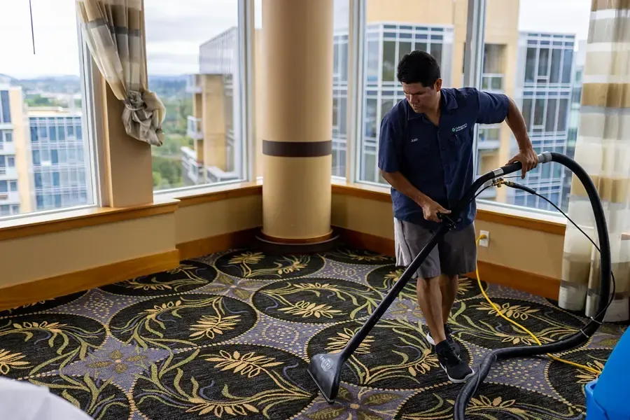Technician extracting water from patterned carpet with a hose and wand