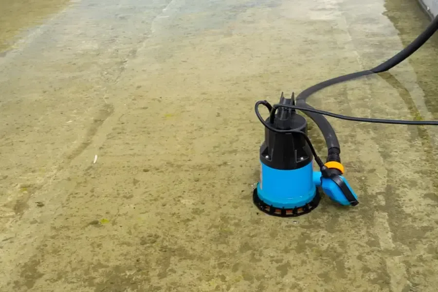 Submersible pump and discharge hose on a wet concrete floor