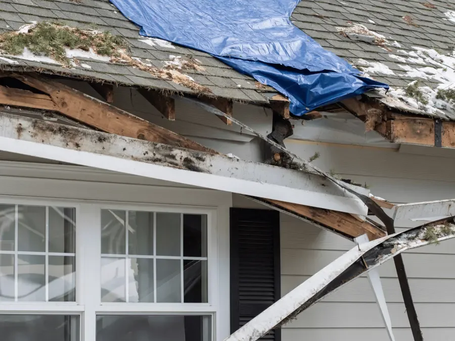 Emergency tarp secured over a storm-damaged roof while rainfall reaches the structure