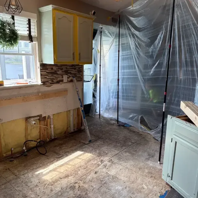 Kitchen with lower cabinets removed and plastic containment installed