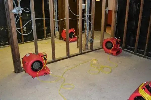 Red air movers drying exposed wall studs and flooring